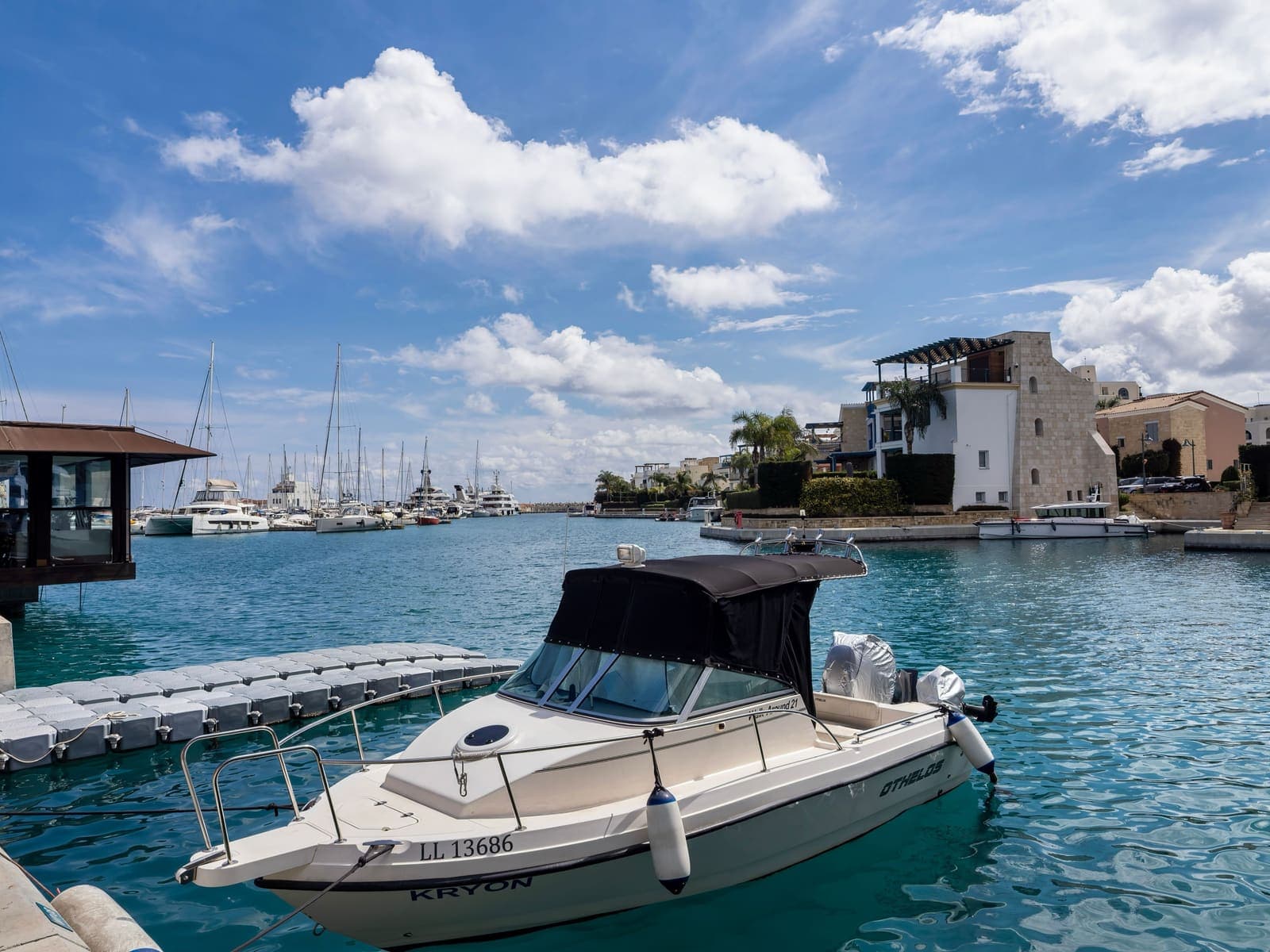 Limassol Marina: a motorboat moored in turquoise water, with yachts and stone-and-white waterfront villas along the canal