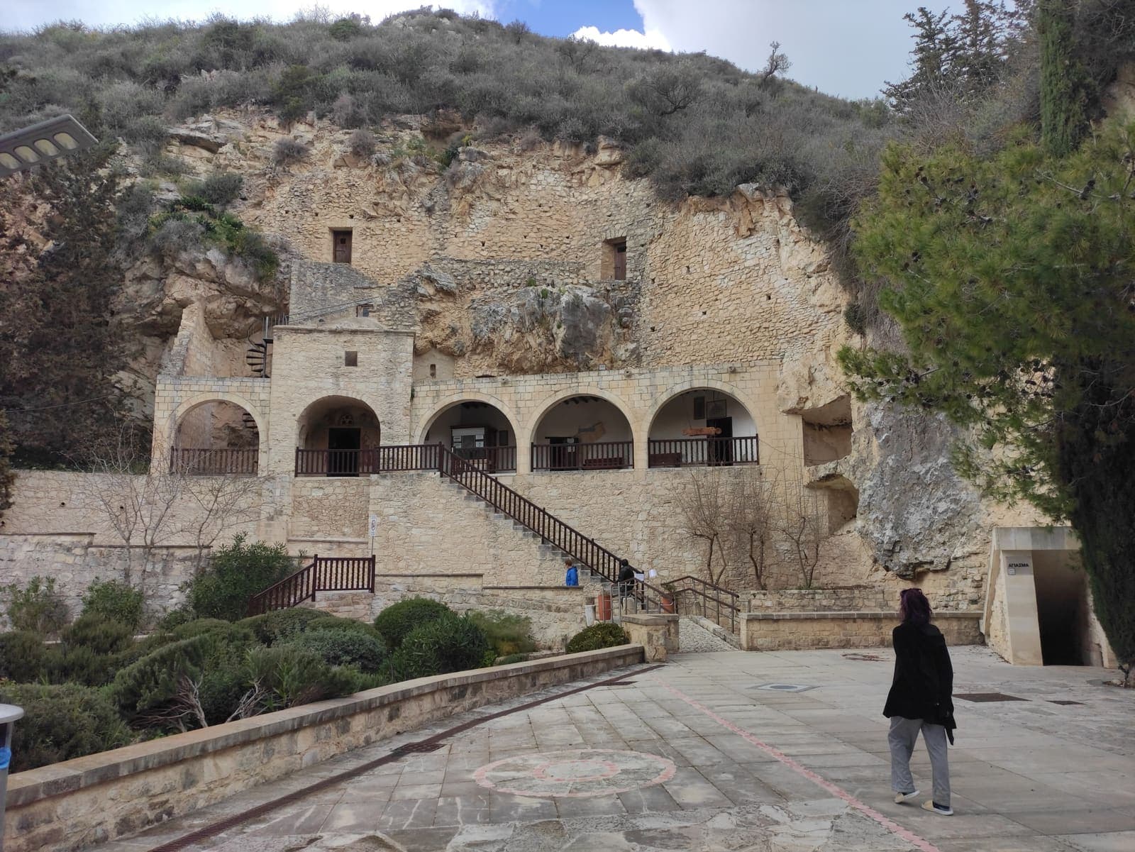 Agios Neophytos Monastery: an arcaded stone building and stairway set against the cliff that holds the rock-cut hermitage